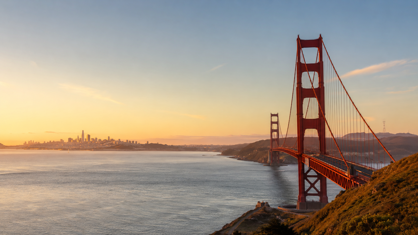 Golden Gate Bridge at golden hour with San Francisco Bay, coastal hills and the city skyline in California.