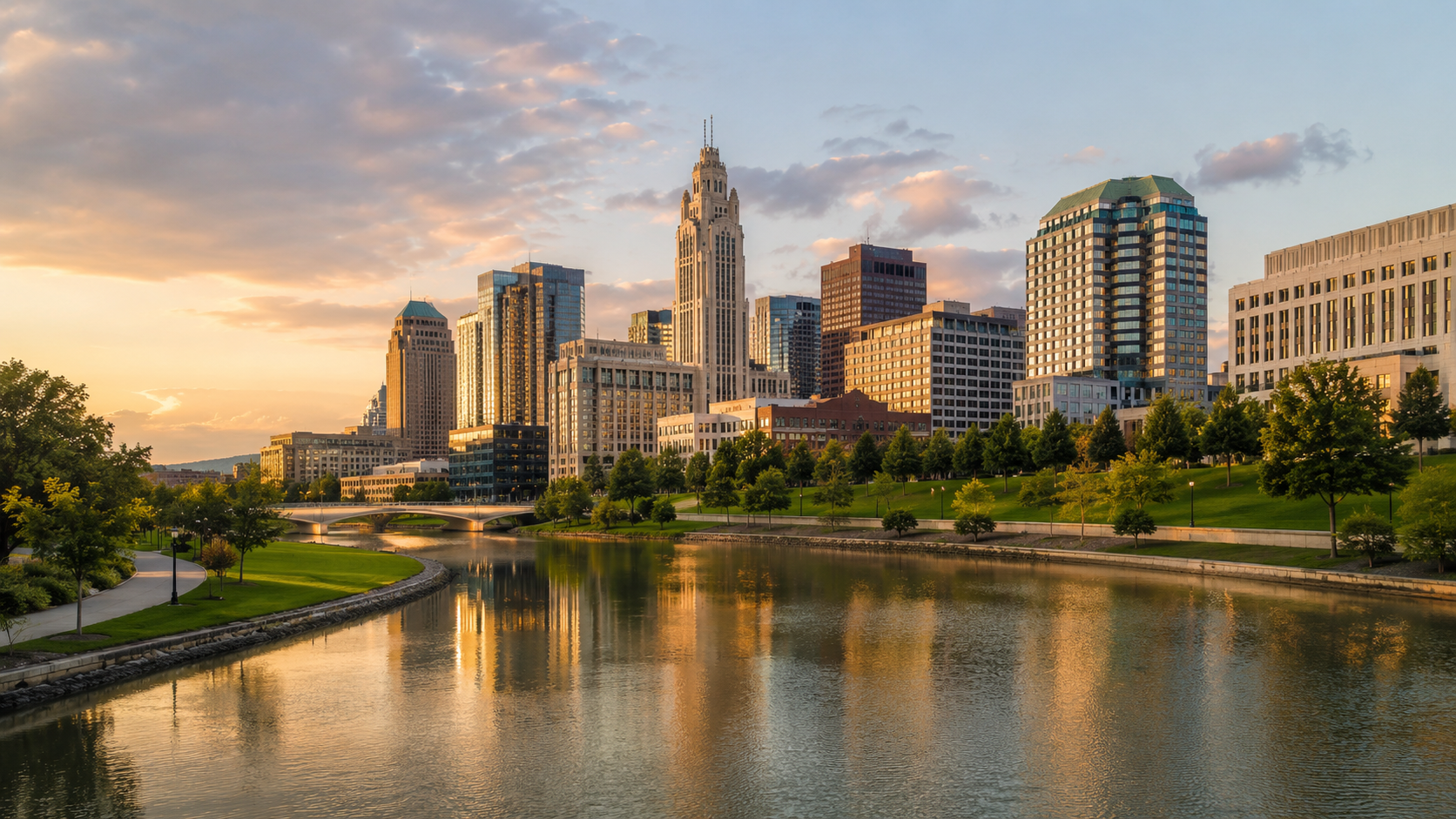 Columbus skyline at golden hour with Scioto River reflections, downtown buildings, green riverfront park and city bridge in Ohio.
