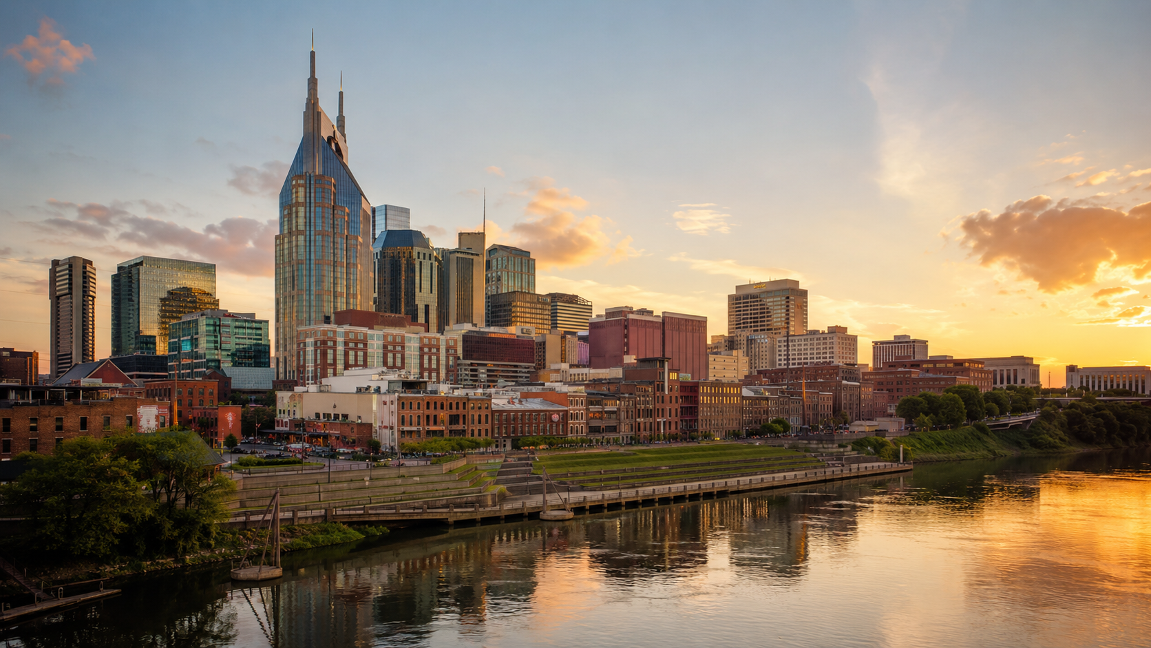 Nashville skyline at golden hour with downtown towers, Cumberland River waterfront and sunset reflections in Tennessee.